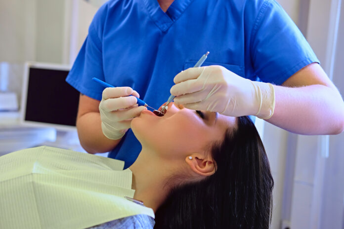Dentist examining female's teeth in dentistry. Estudo apontou que úlceras aftosas e lesões herpéticas foram problemas frequentes de pessoas com covid-19