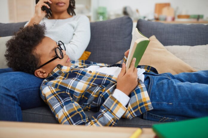 African Boy Reading Book on Couch